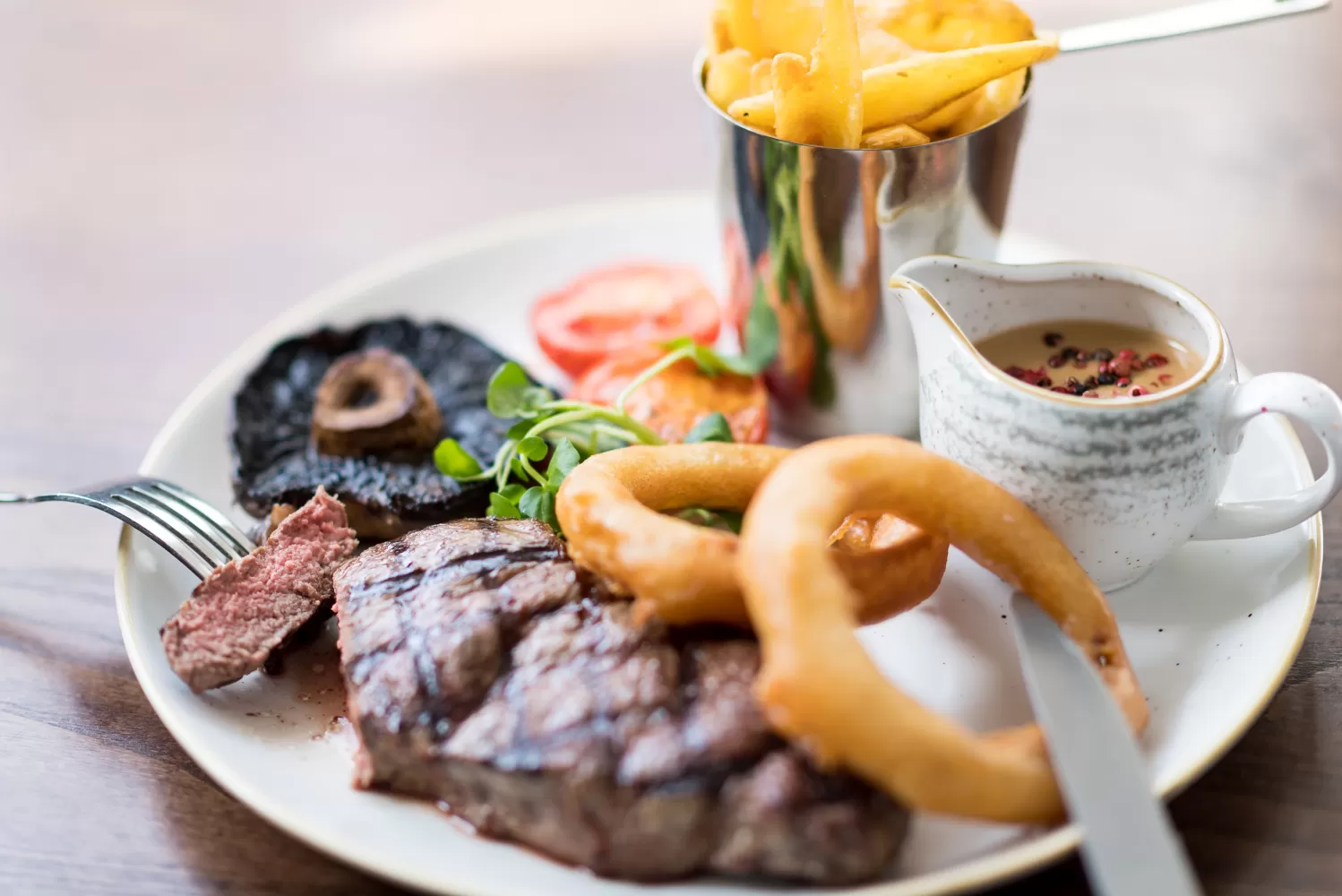 A large steak served with onion rings, chips, flat mushrooms, tomoato and a wholegrain mustard sauce at Barnstaple Restaurant 62 The Bank