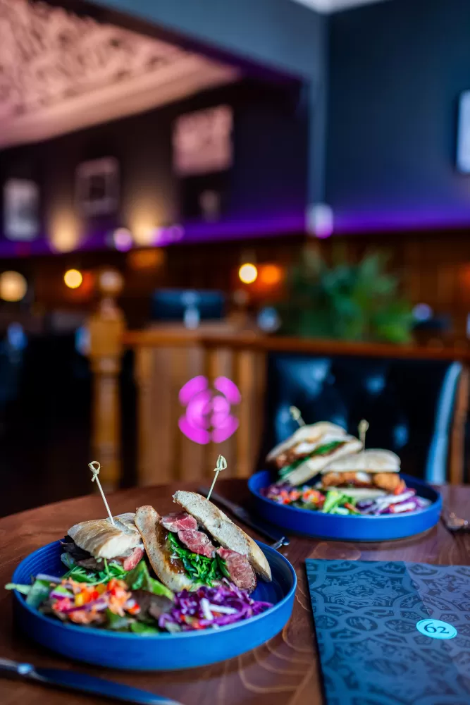 A steak sandwich and restaurant menu on a table