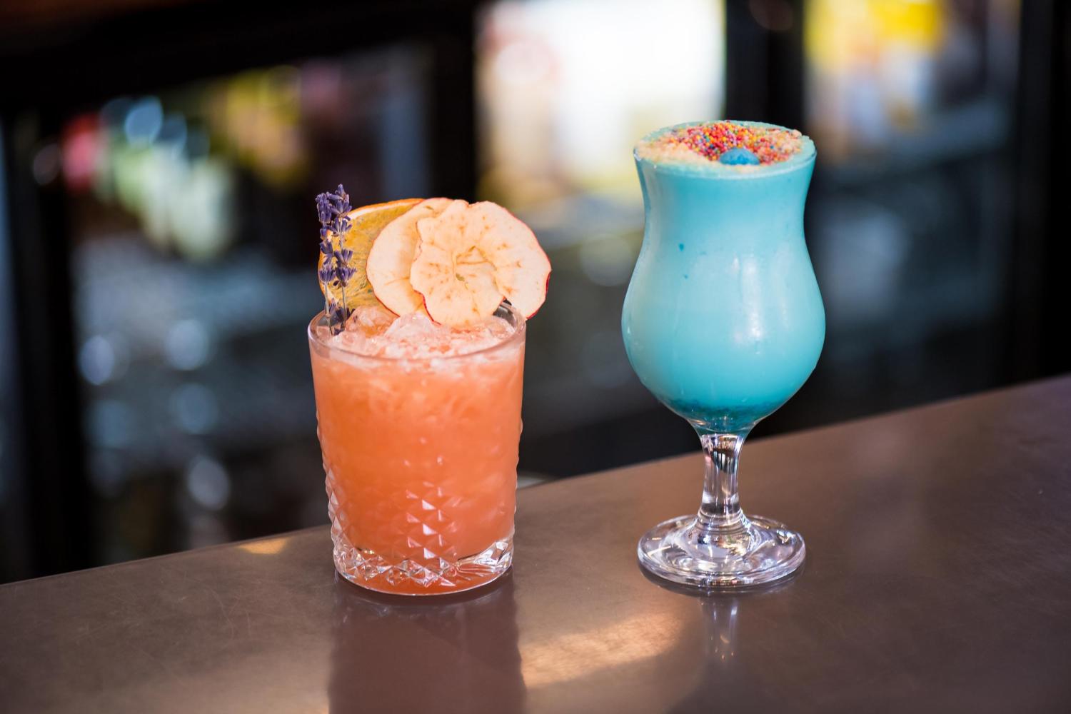 Two fresh cocktails sitting on a bar top