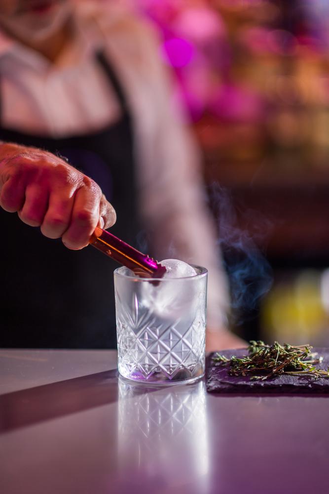 Mixologist putting ice in glass