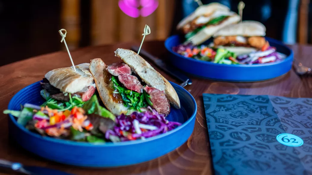 A steak sandwich and restaurant menu on a table