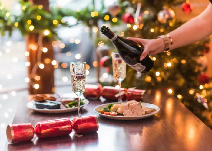 Waitress pouring a glass of Prosecco with starters and Christmas decorations also on table