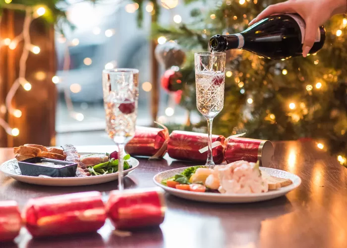 Waitress pouring a glass of Prosecco with starters and Christmas decorations also on table